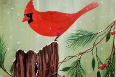 A cardinal on a tree stump with pine branches and berries around it.