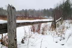 A picture of a field and old wooden fence in the snow.